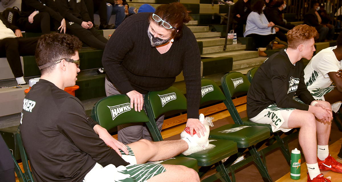 Athletic trainer helping injured athlete at basketball game