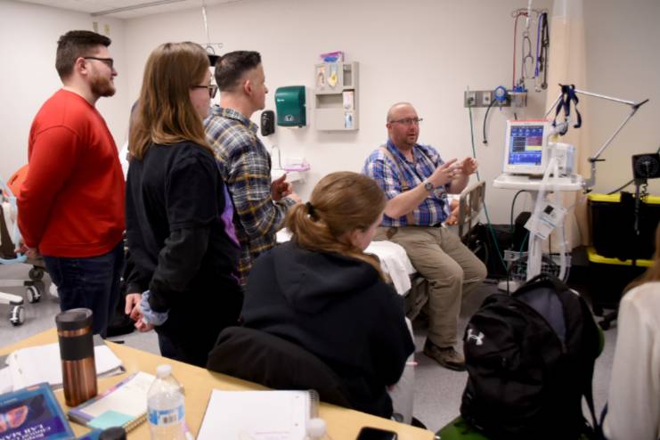 faculty member Michael Brown with students in lab faculty member surrounded by students in the respiratory lav