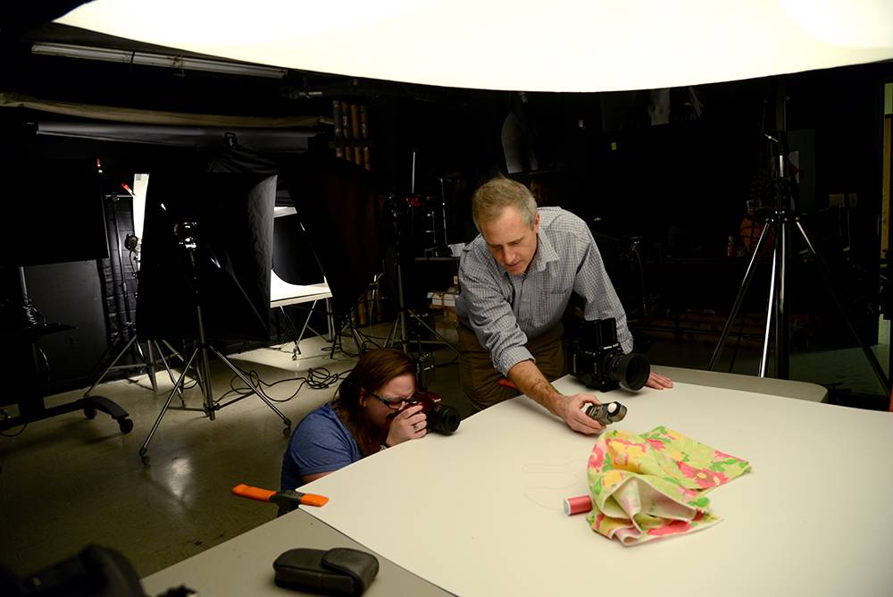 Photography instructor helping student with lighting