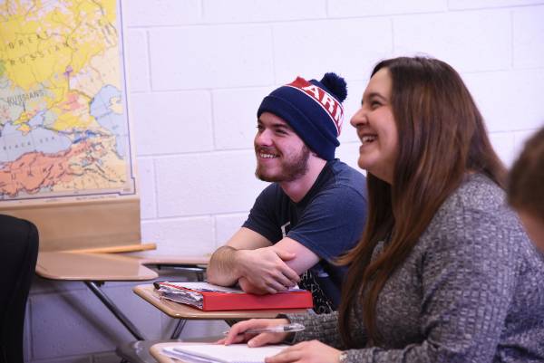 Two students sitting in class, smiling