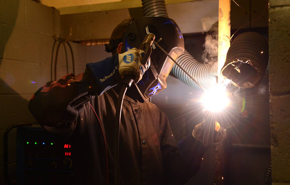 Welder using tools in lab