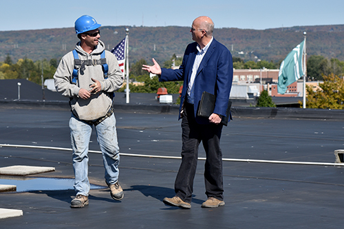 Christopher Crolius talking with team on roof at MVCC campus