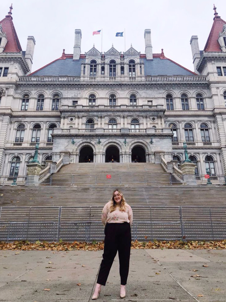 Image of MVCC alumna Taryn Rackmyer standing in front of the NYS Senate Building