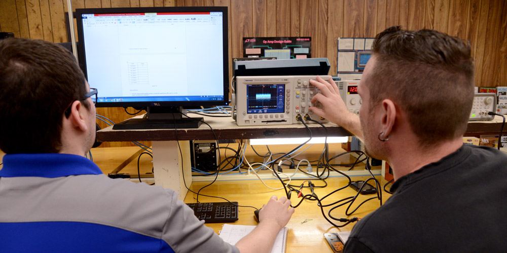 Students testing circuits using precision testing machines in classroom