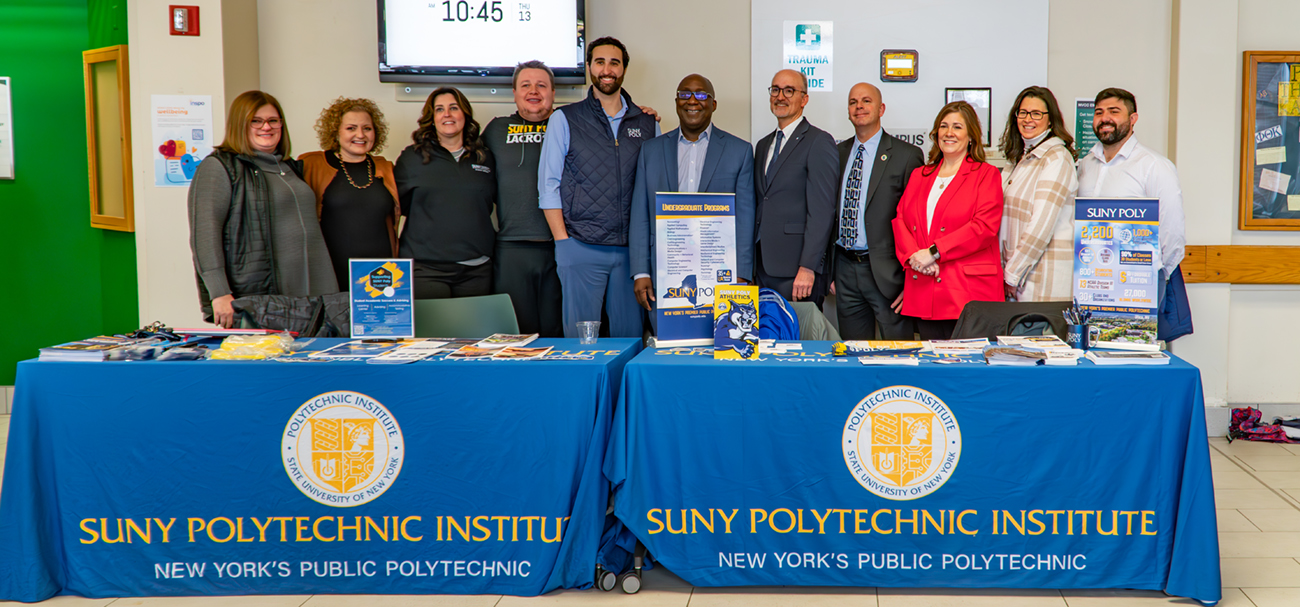 Group of people standing behind SUNY Polytechnic Institute table at MVCC