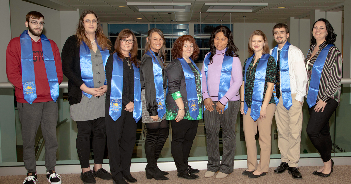 Group of students smiling, wearing blue Spire honor society sashes