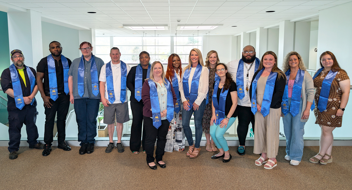 Group of people standing in a row wearing blue Spire honor society sashes