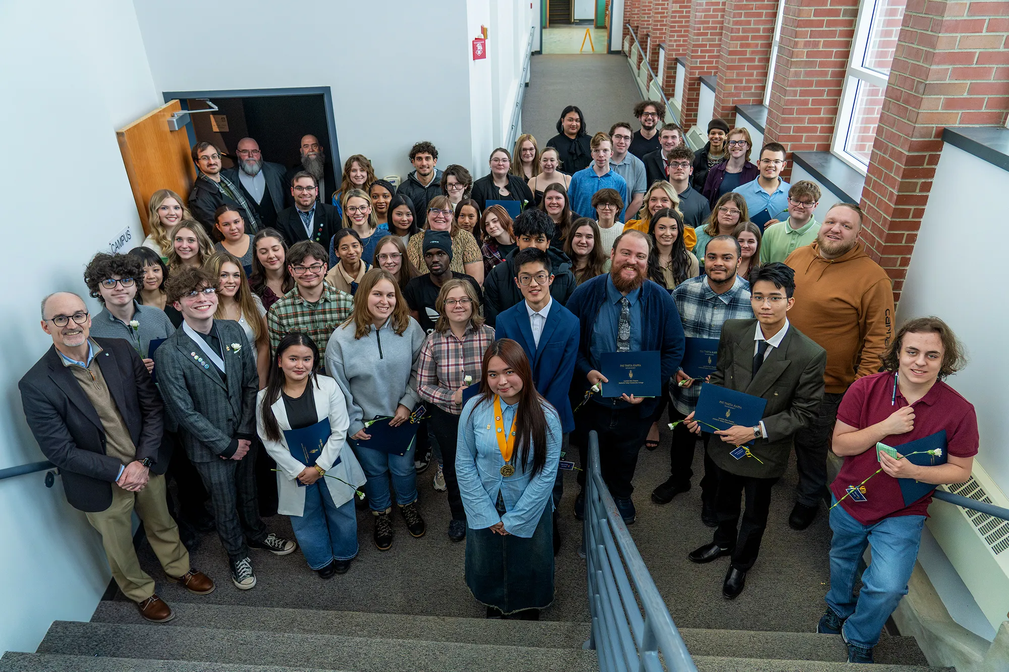 Group of MVCC students, faculty and staff standing on stairs, looking up, smiling