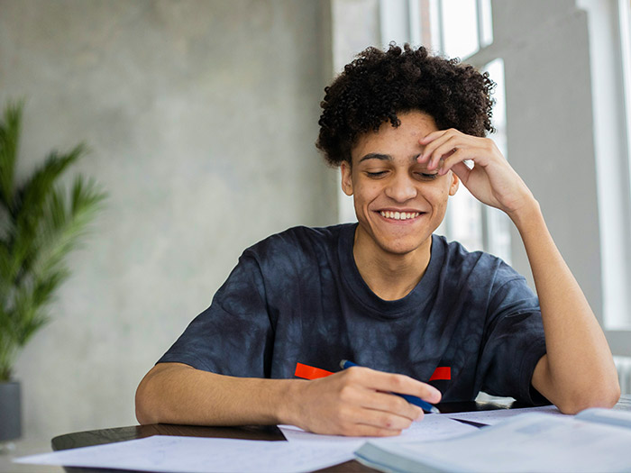 man sitting at a desk writing and smiling