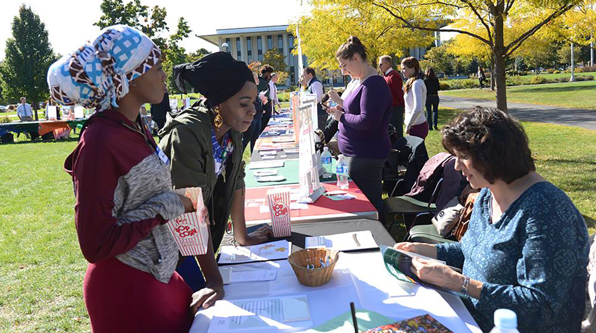 Students talk with college representatives at a table outside